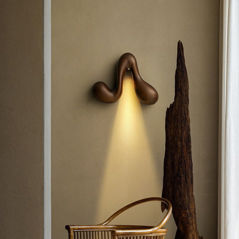 Sconce lit beside a woven basket and a tall carved wood floor piece