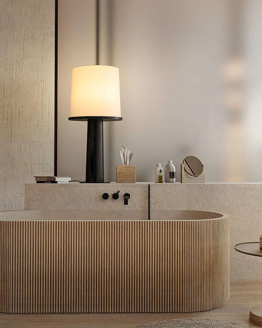 The black version lit on a ribbed vanity beside a round mirror