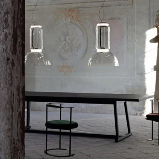 Two stacked cylinder pendants lit above a console with a chair