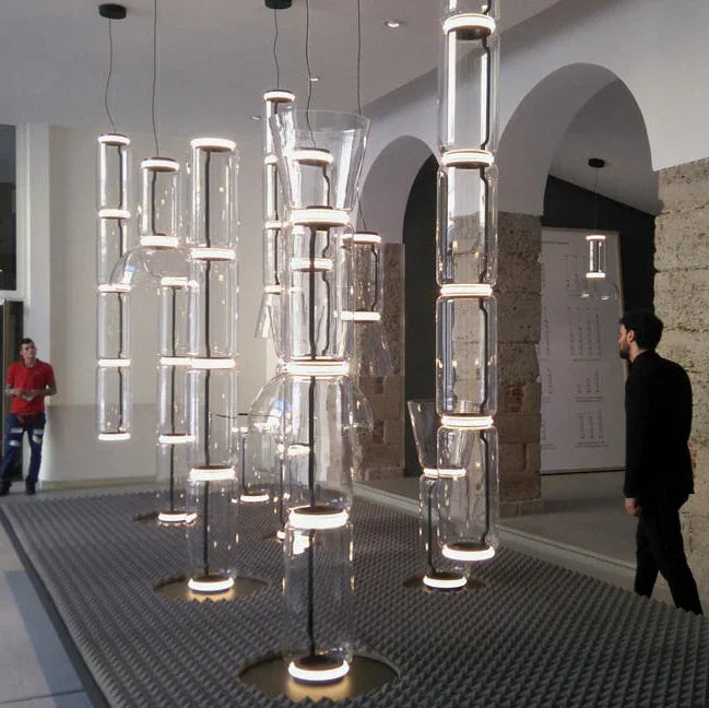 Tall stacked cylinder pendants lit in a stairwell beside an archway
