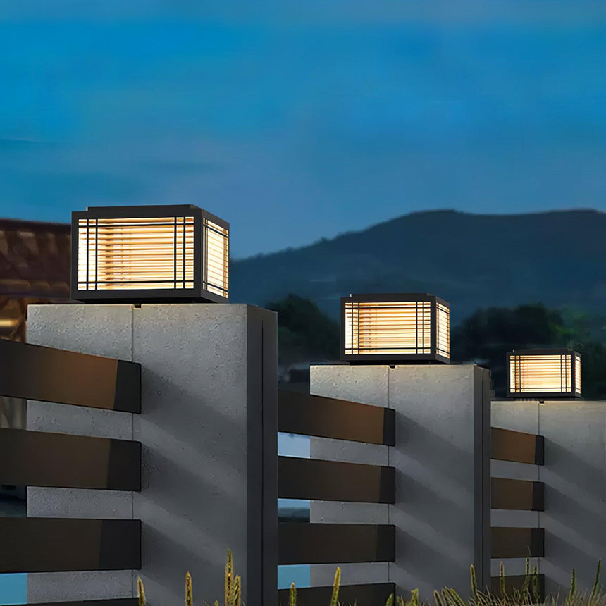 Two caps lit on pillars with hills and an evening sky behind them