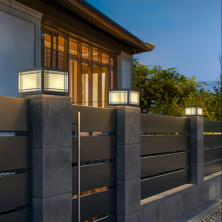 The cap glowing on a pillar beside a timber clad house at dusk