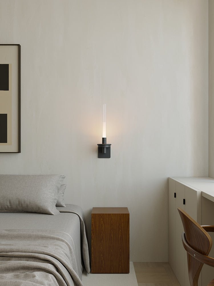 Lit in a bedroom between a framed print, a made bed and a small desk