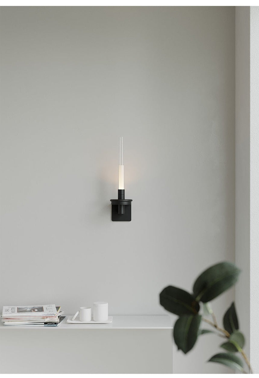 Lit above a white shelf holding a small plant, a stack of books and a tray