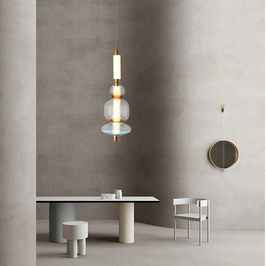 The stacked bead pendant lit above a round dining table beside a chair