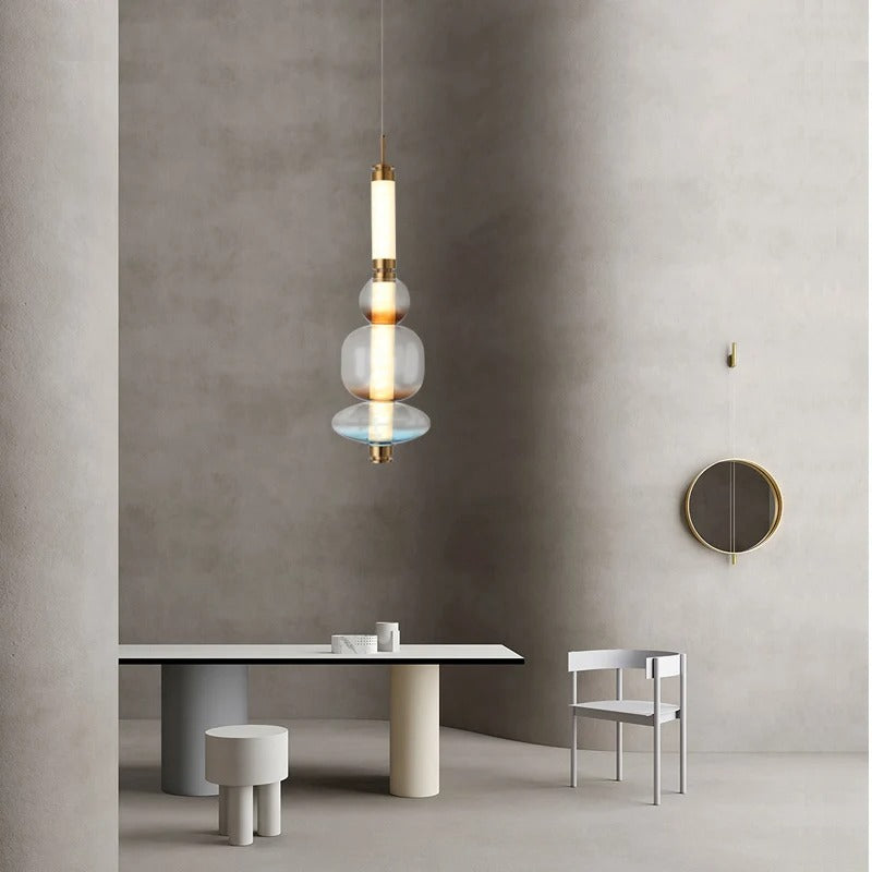 The stacked bead pendant lit above a round dining table beside a chair