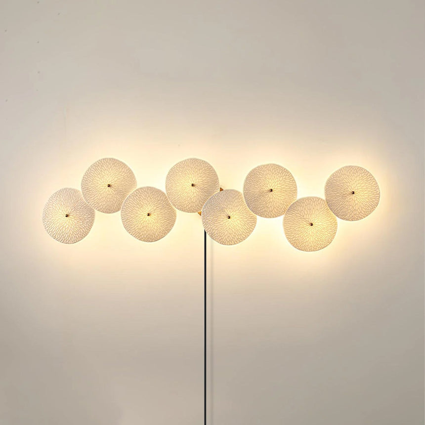 Eight discs in a long horizontal row glowing on a warm wall