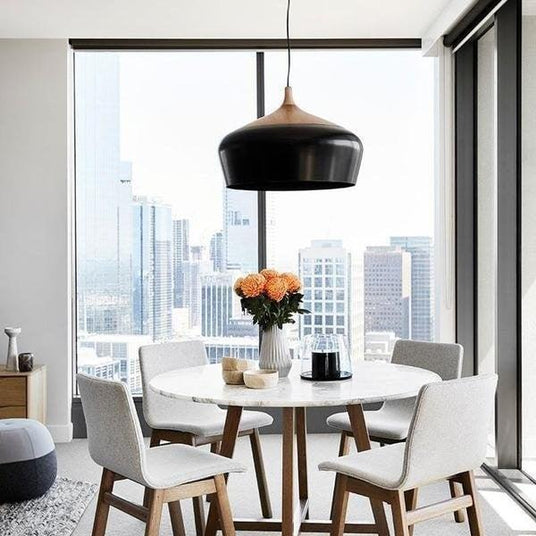 Black dome hung above a dining table by a window