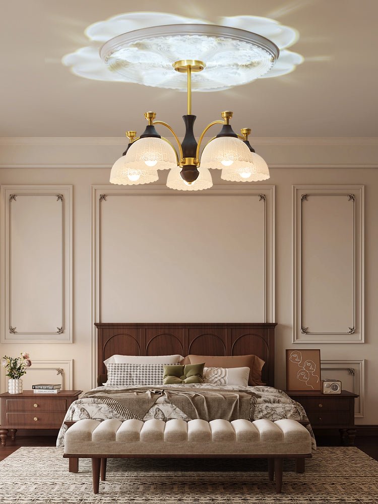 Domes lit above a made bed in a room with wall panels behind it