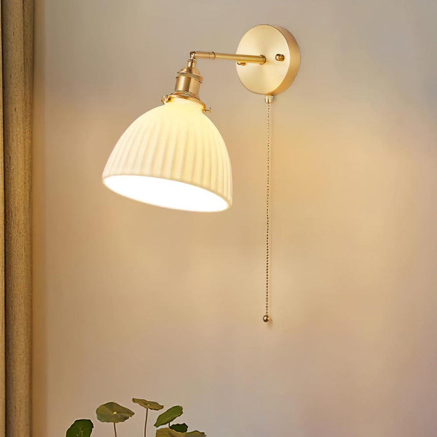 The dome shade lit warm on a beige wall, the pleats glowing