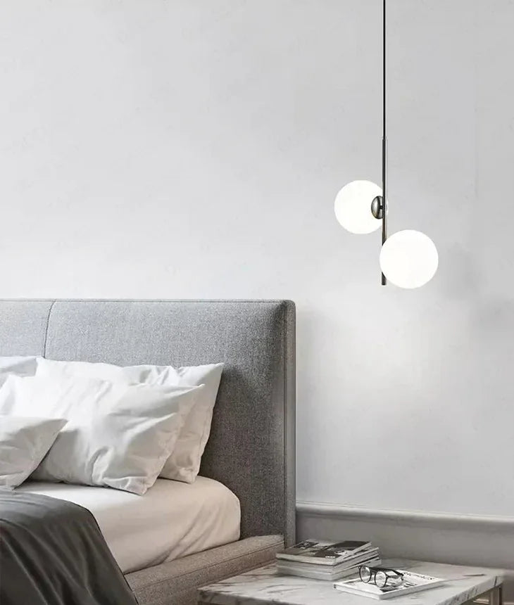 Opal globes lit beside a bed with a soft upholstered headboard