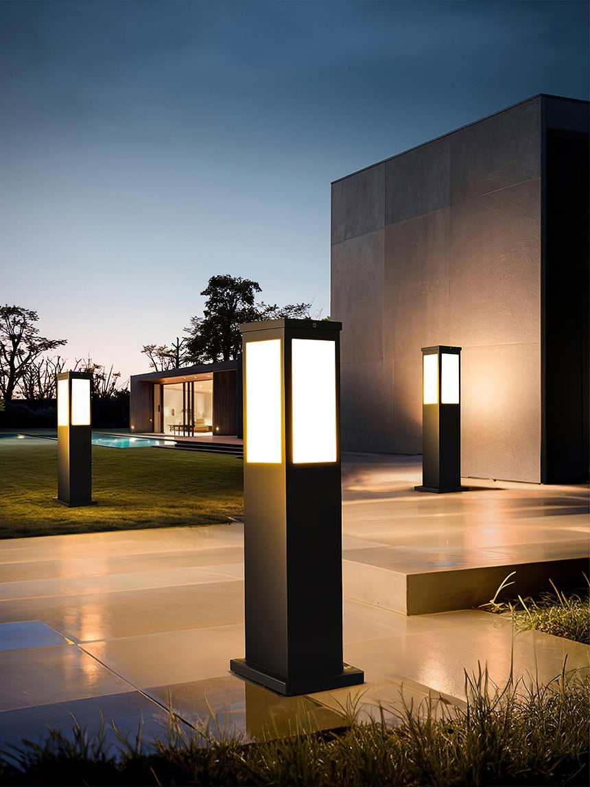 Two lit beside a dark pool with a lit house wall behind them