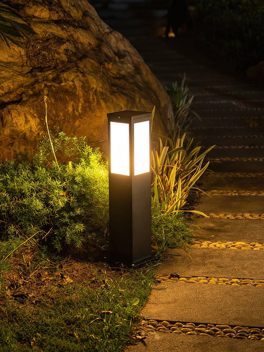 The bollard lit beside rock steps with grasses and gravel around it