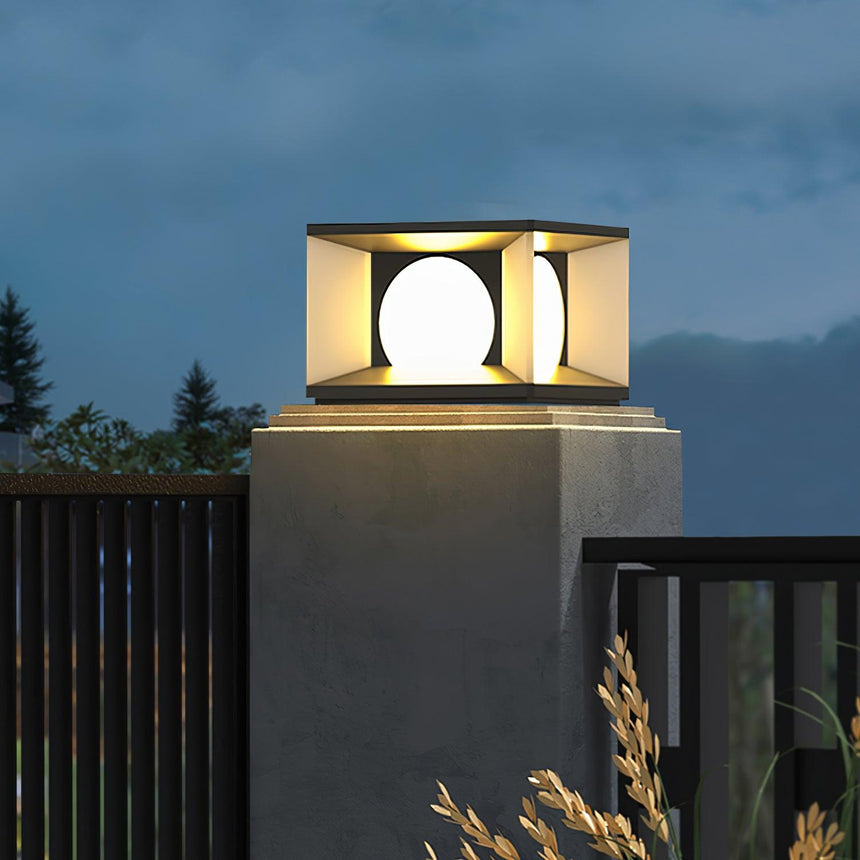Cubes lit on two pillars with hills and an evening sky behind them