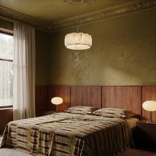A lit stone drum in a green bedroom above a bed and headboard