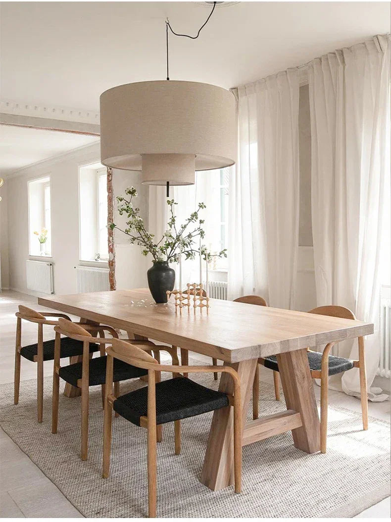 Drum shade pendant light hung over a long wooden dining table