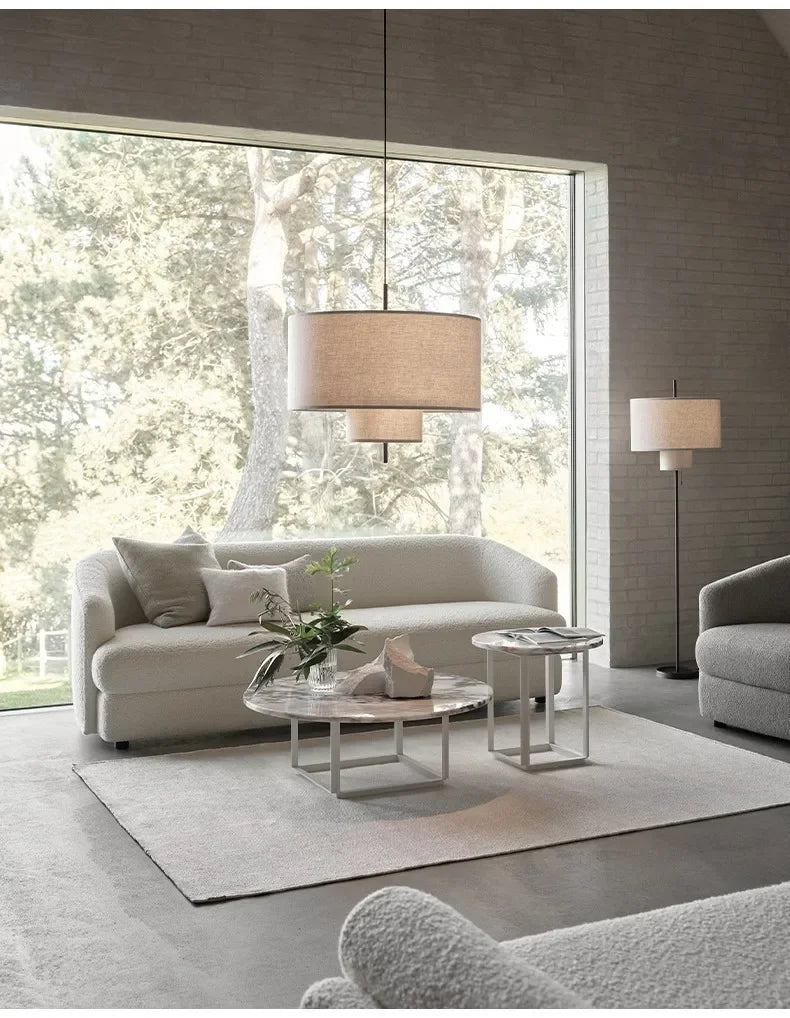 Drum shade pendant light in a living room beside a window seat