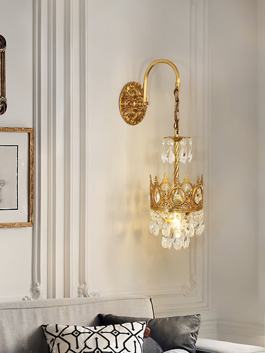The crown sconce lit on a paneled wall above a sofa with patterned cushions