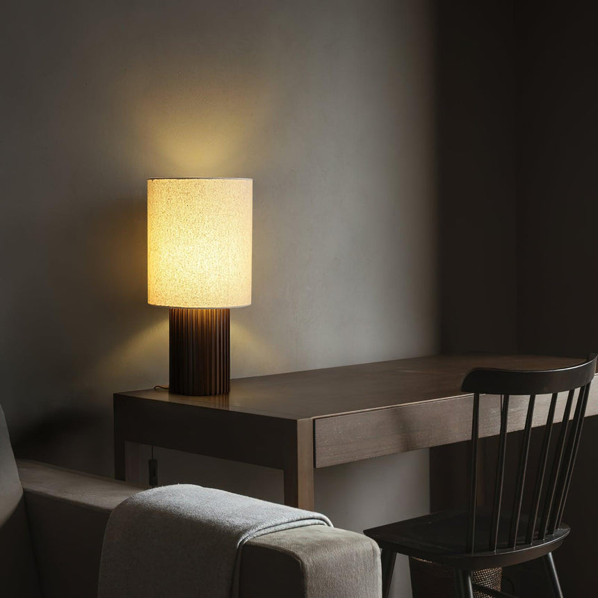 Entryway table lamp lit on a console in a dim hall beside a chair