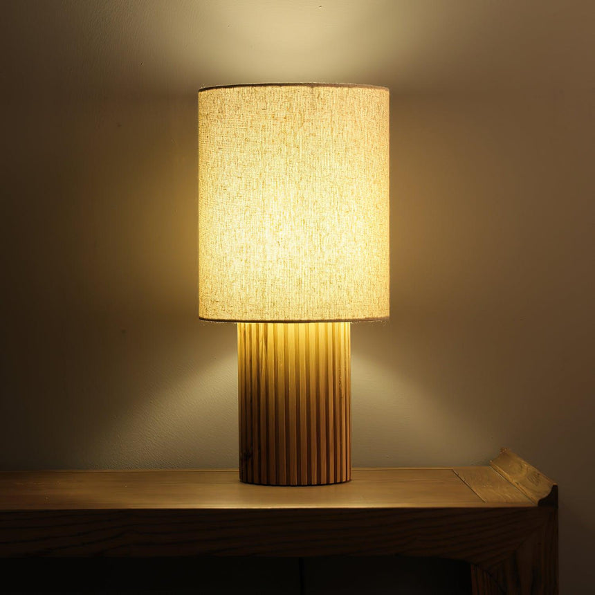Entryway table lamp lit on a wooden console against a dark wall
