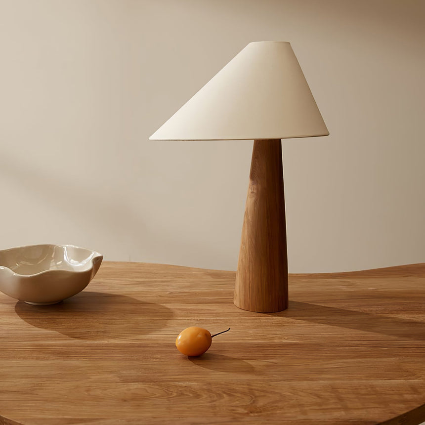 Wood cone lamp unlit on a round wood table beside a small bowl