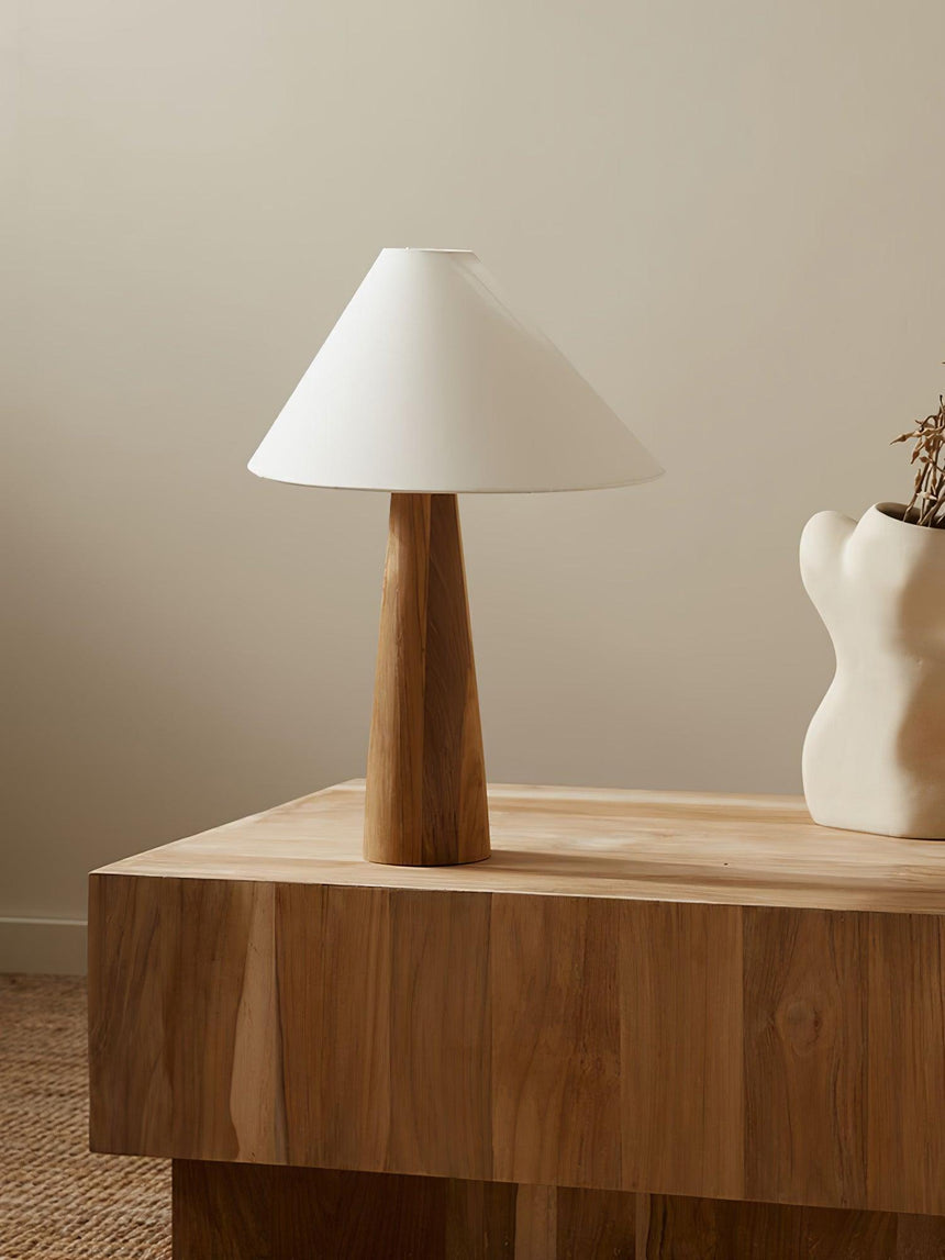 Wood cone lamp unlit on a console beside books and reading glasses