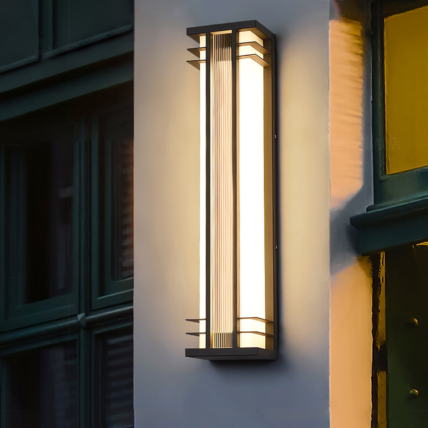 A tall box light glowing beside a dark green front door and a window
