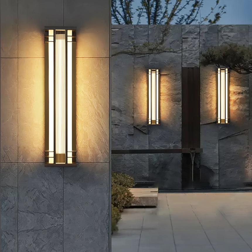 Box lights lit on a slate wall beside an entry path and a planted bed