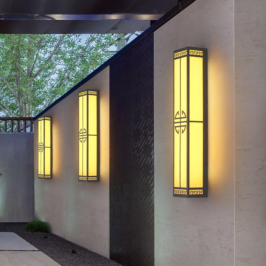Tall lanterns along the wall of an open air corridor beside a tree