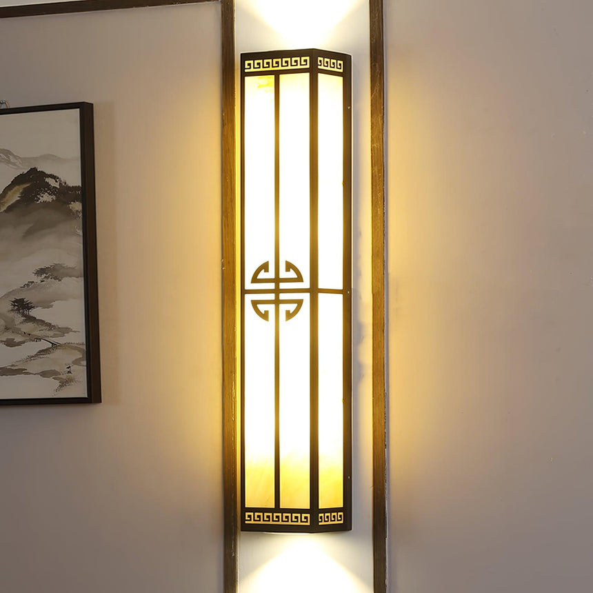 The lantern lit between wall panels beside a framed landscape painting