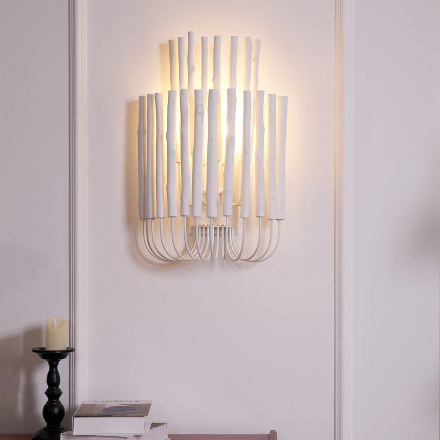 Rod sconce lit warm on a paneled wall, the light spilling upward