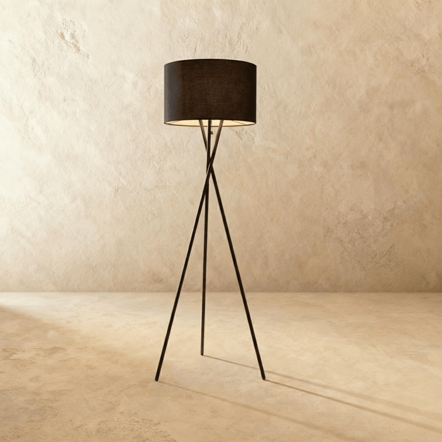 The same crossed tripod carrying a black fabric drum shade above three thin legs