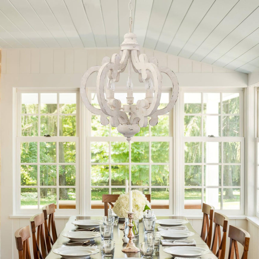 Chandelier lit above a set dining table in a room with tall windows