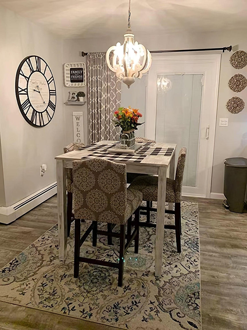 Chandelier lit in a hallway above a rug and a wall clock