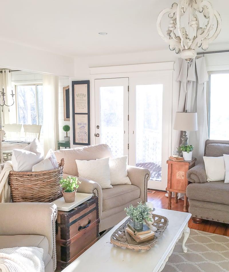 Chandelier lit in a living room above a pale sofa and a chest