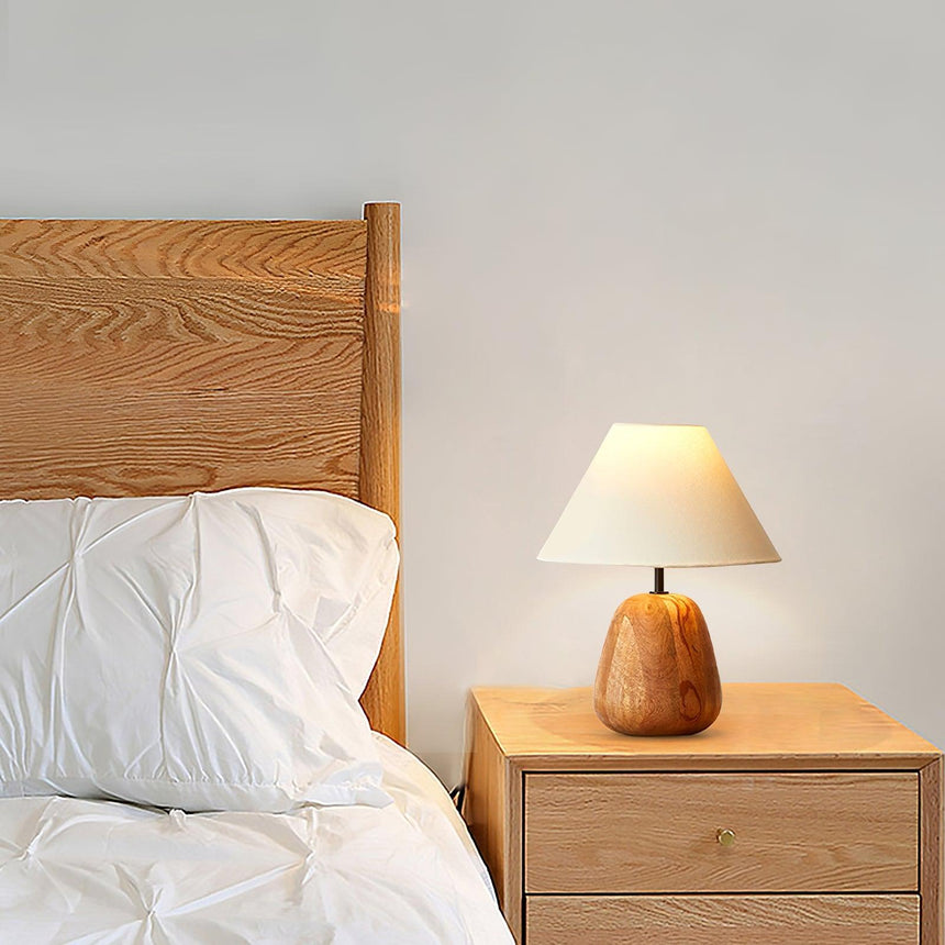 Large farmhouse table lamp lit on a pale table beside two small books