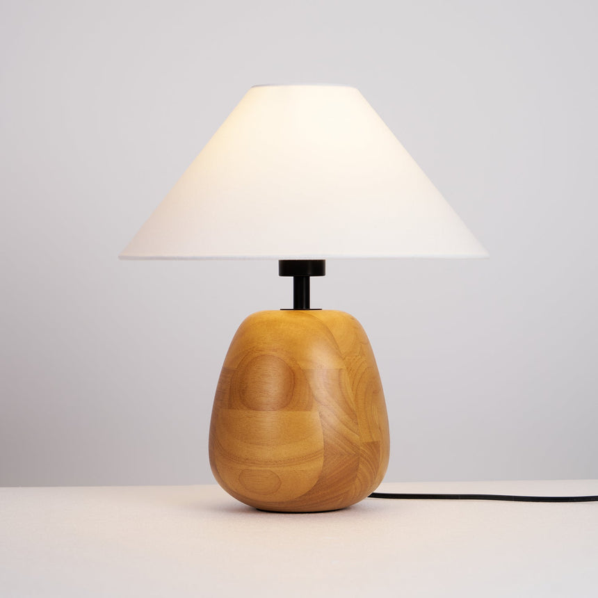 Farmhouse table lamp lit on a nightstand in a warm bedroom at night