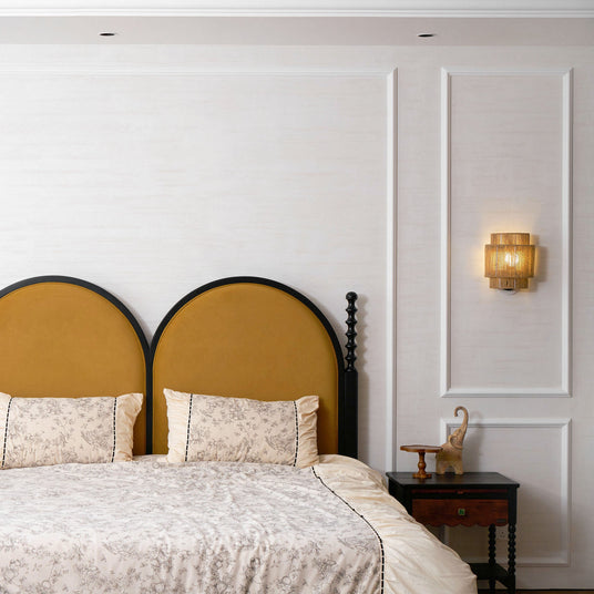 The hemp lamp lit on a paneled wall beside a bed with an arched mustard headboard