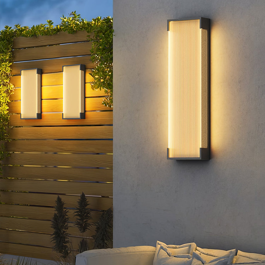 A pair lit on a timber screen behind a garden sofa with cushions