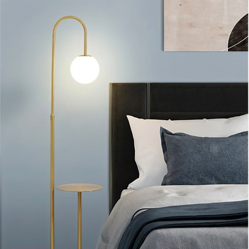The lit globe beside a bed with blue and white bedding and a dark headboard
