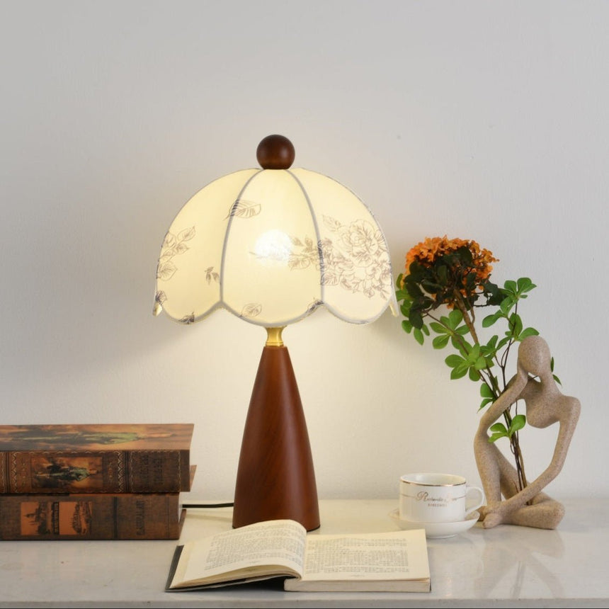 Floral table lamp lit close, the scalloped shade edge in view