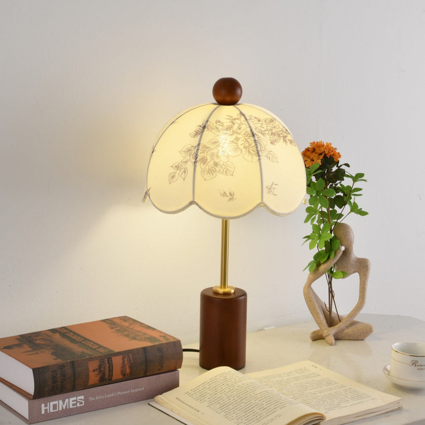Parasol shade lamp lit on a desk beside an open book and a cup