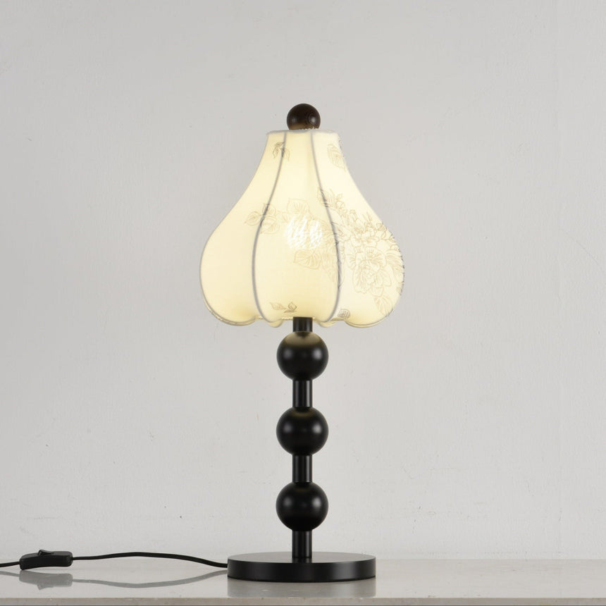 Black floral table lamp lit, the petal shade glowing warm from inside