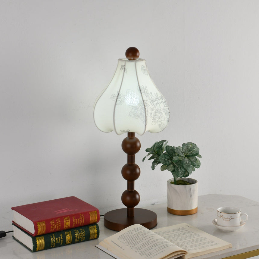Walnut floral table lamp unlit beside a small plant and a stack of books