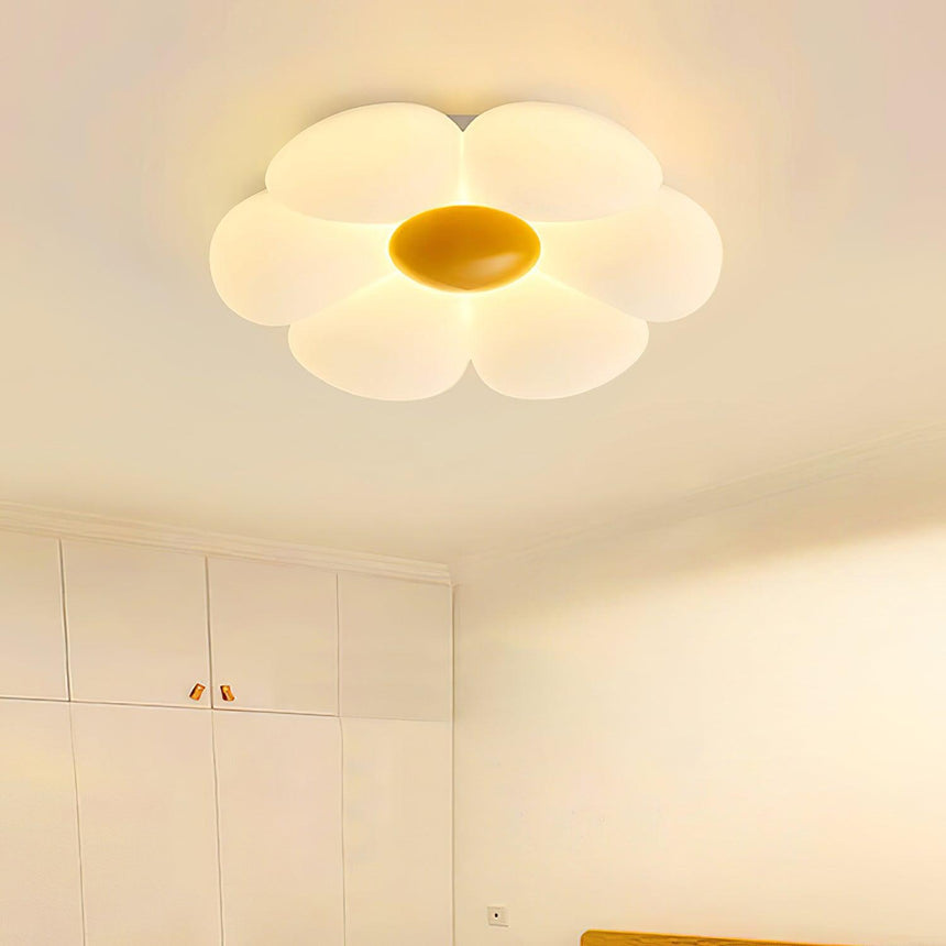 Flower ceiling light with a yellow center lit in a pale bedroom