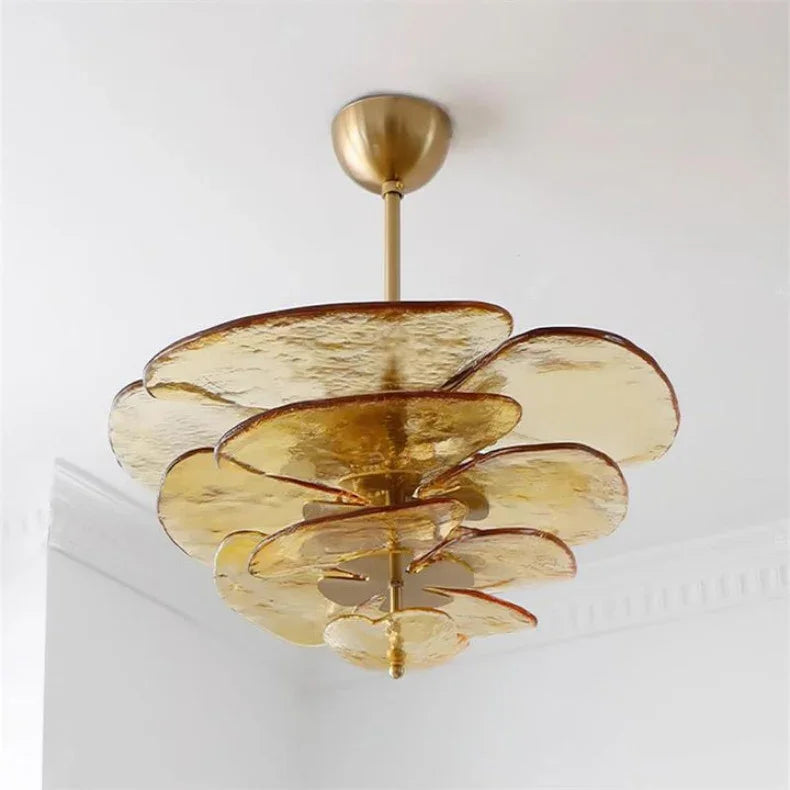The amber glass petal shade lit close under a white ceiling in a pale room