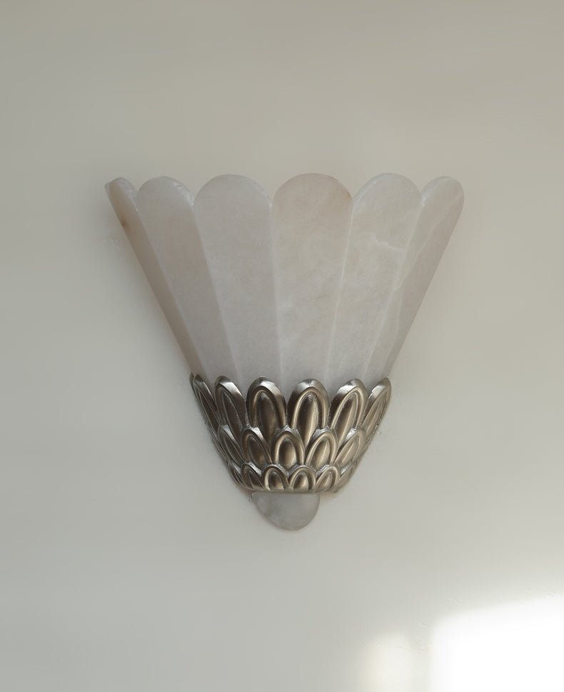 The sconce unlit, showing the pale stone fan and the silver petals