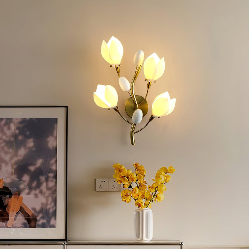 The lit magnolia light above a white console with a vase of yellow flowers