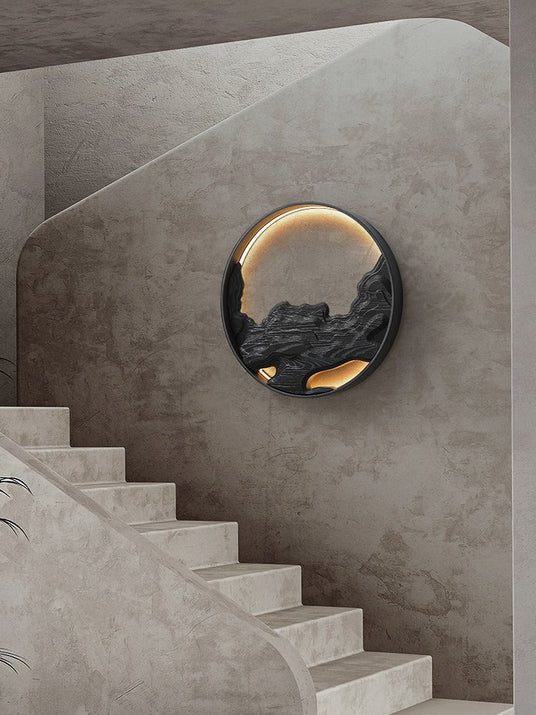 Carved disc lit on a stairwell wall beside a run of pale stone steps