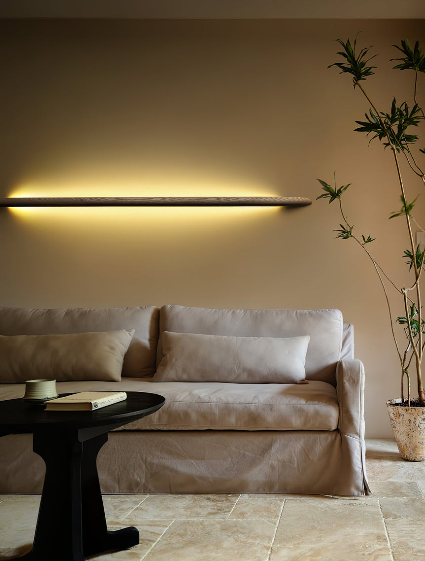 Rod lit horizontally above a pale sofa beside tall bamboo stems